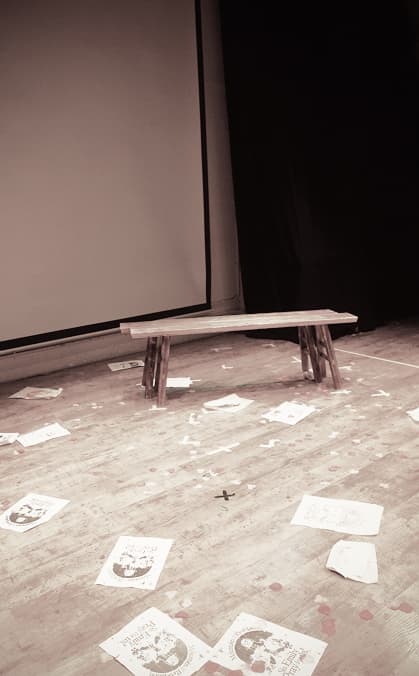 image of a bench onstage with scattered paper on the floor